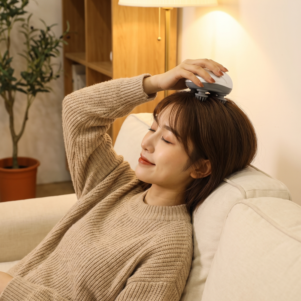 Woman relaxing on the sofa with the Himra scalp massager