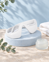Himra eye massager on a blue stone plinth with eye gel and eucalyptus