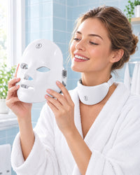 Woman in a bathrobe about to put on the Himra LED face mask, neck piece already on